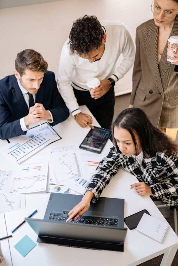 pexels photo 7693697 Team of colleagues discussing financial charts at a laptop in an office setting.