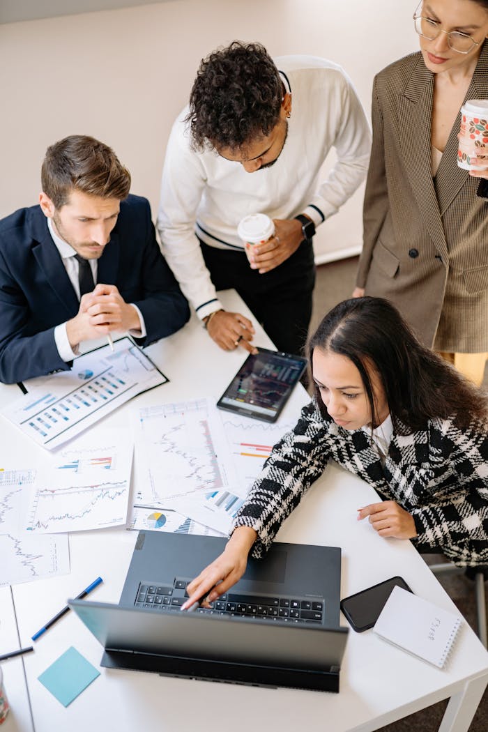 services-05 Team of colleagues discussing financial charts at a laptop in an office setting.